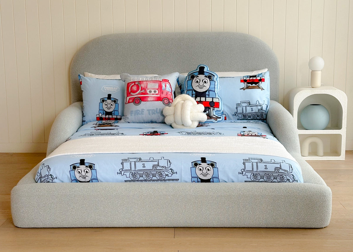 Children's bed with Thomas the Tank Engine bedding set in a room with wooden flooring and a white wall.
