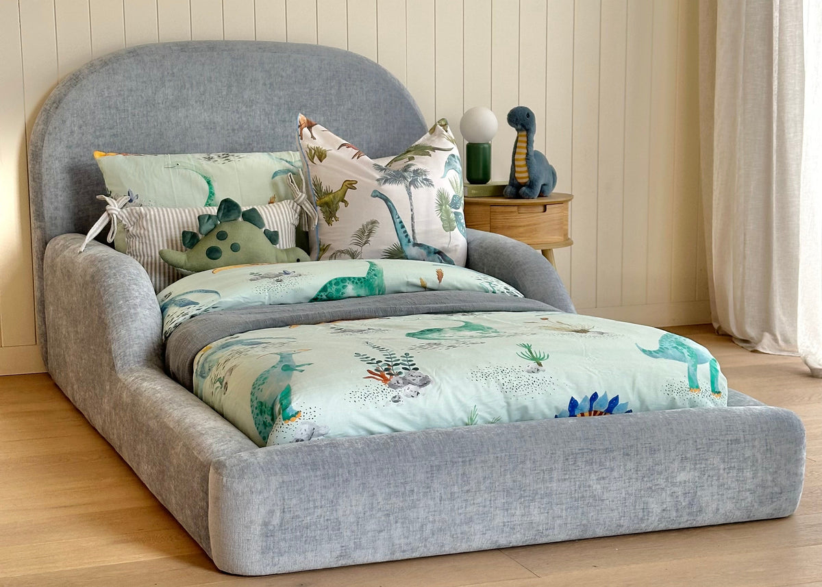 Blue kids bed side view dresses in dinosaur themed linen