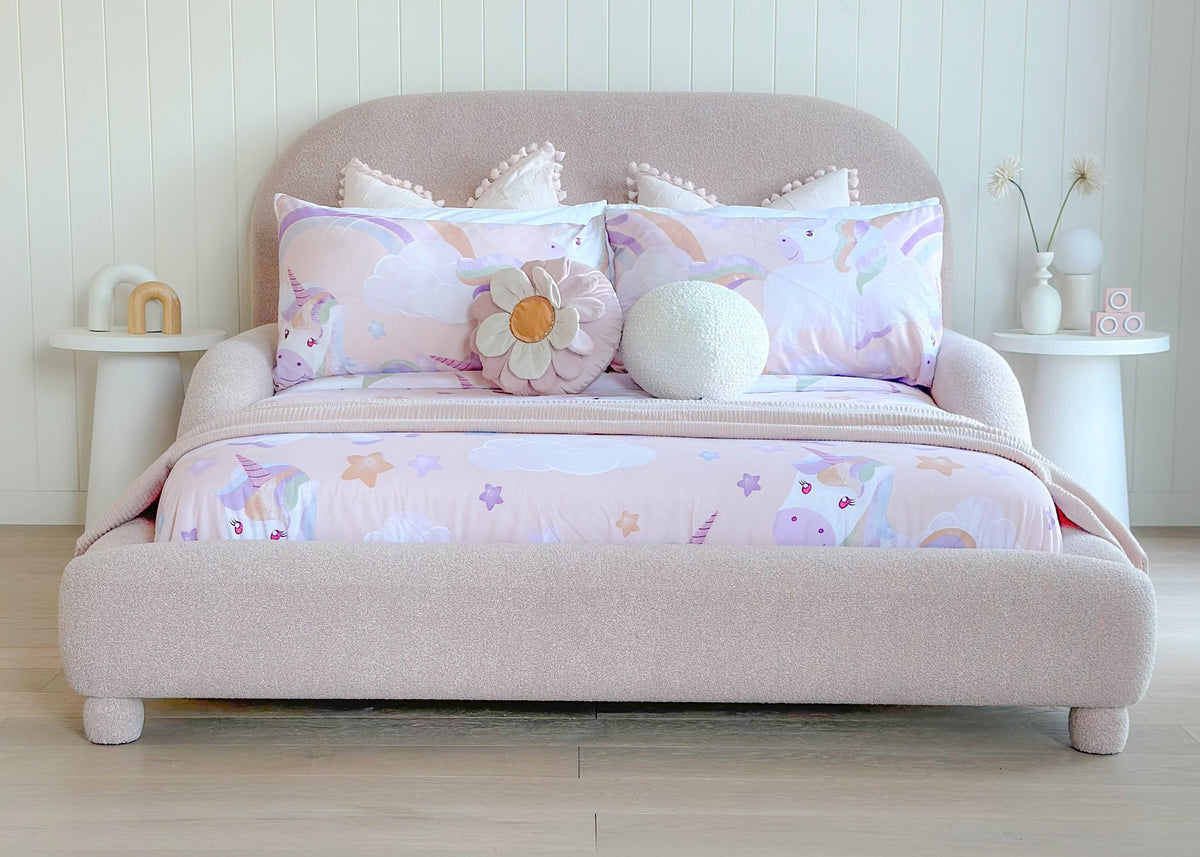 Padded toddler bed in dusty pink fabric with cozy bedding and plush cushions