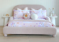 Padded toddler bed in dusty pink fabric with cozy bedding and plush cushions