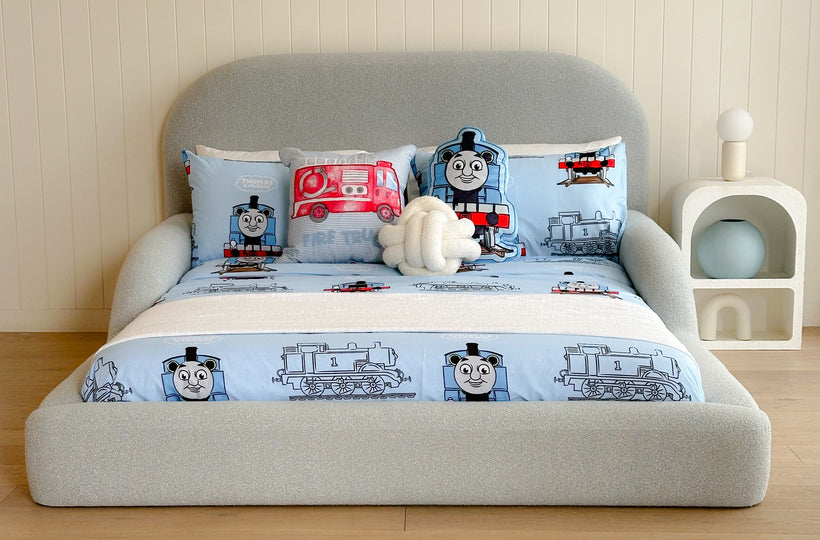 Children's bed with Thomas the Tank Engine bedding set in a room with wooden flooring and a white wall.