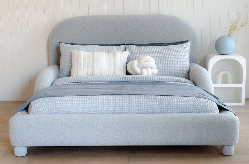  Upholstered blue kids bed with bedding in a minimalistic room.