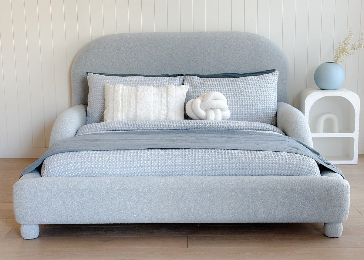  Upholstered blue kids bed with bedding in a minimalistic room.