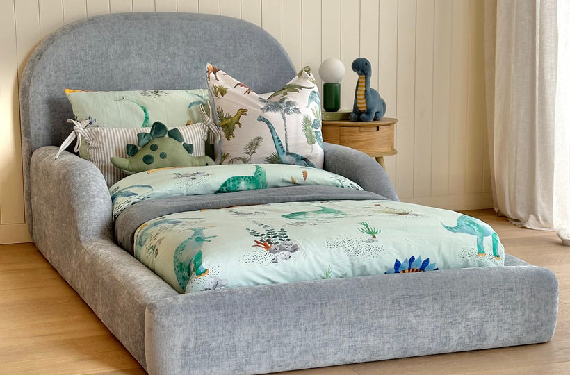 Blue kids bed side view dresses in dinosaur themed linen