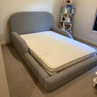 Gray Bed with a Eco Kids mattress on it in a room setting.