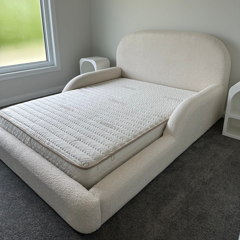 White upholstered headboard against a gray wall with a window in the background