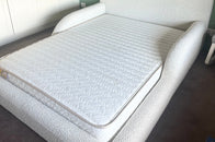 White upholstered bed in a room with geometric wall design