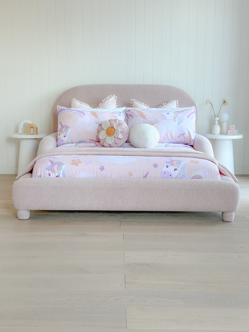 Padded toddler bed in dusty pink fabric with cozy bedding and plush cushions