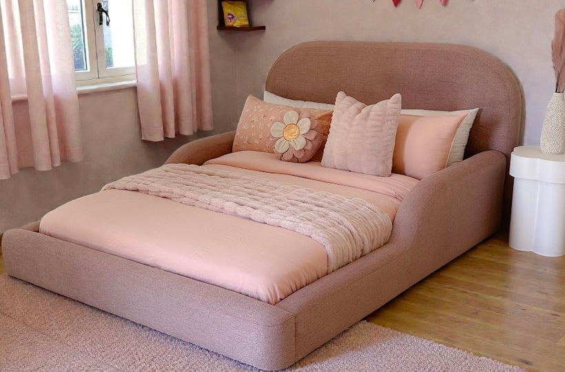 Pink bed in a room with a window, shelves, and decorative flags.